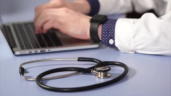 Close Up of Doctor Working at the Workplace. Clinic Worker Typing on Laptop.