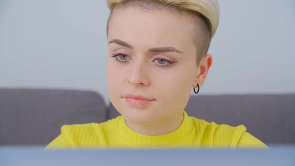 Portrait of short haired young female working on laptop computer at home on lockdown in 4k video