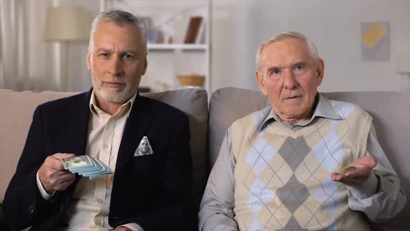 Rich Elderly Man Showing Bunch of Dollars, Poor Senior Friend Showing Coins