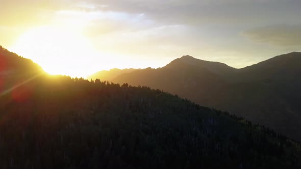 Aerial drone view of a beautiful fall sunset with the sun gleaming over the mountain timberline in t