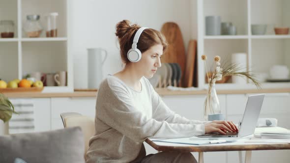 Young Woman in Headphones Messaging on Laptop while Working from Home