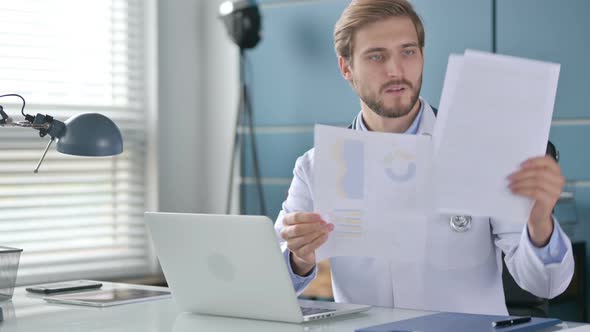 Doctor with Laptop Reading Documents in Clinic