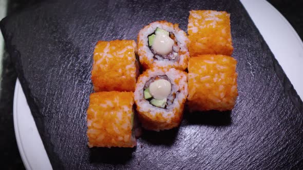 Top View of Fresh Sushi Rolls Rotating on Black Stone Slate Plate