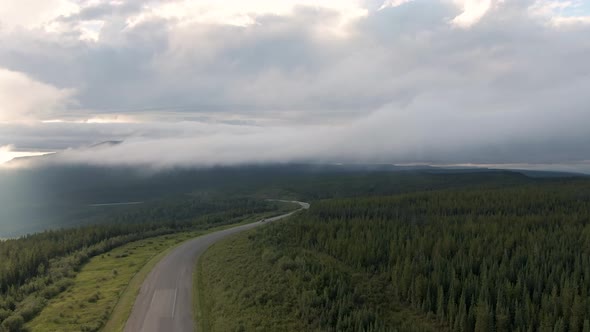 Beautiful View of Scenic Road From Above Surrounded By Lush Forest, Clouds and Mountains