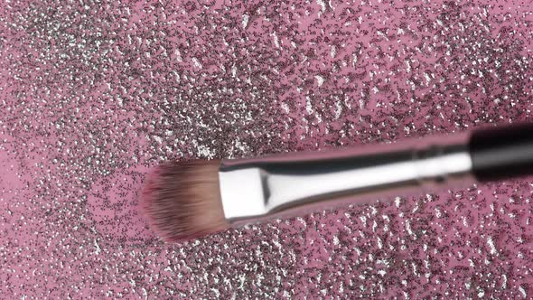 Smearing Silver Glitter on a Pink Background Gloss Powder Closeup