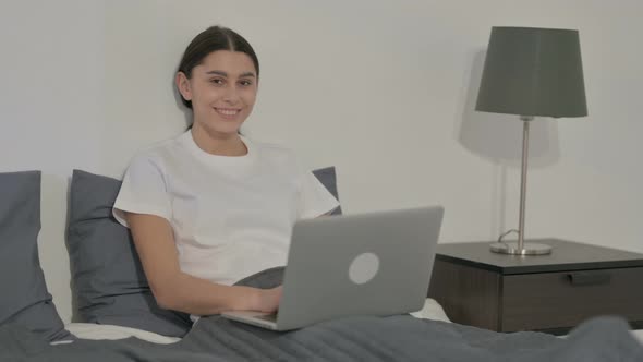 Indian Woman Looking at Camera while using Laptop in Office