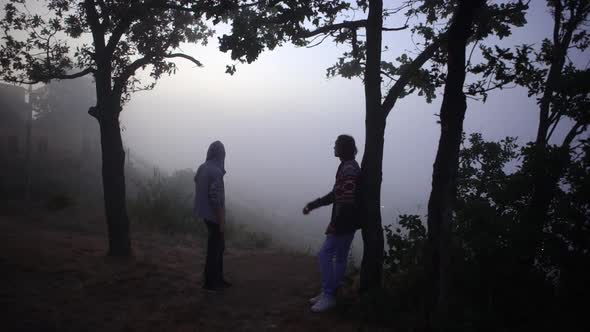 From Above Young Slim Man Throwing Up Hacky Sack Standing Under Trees on Hill Over Sea Covered with