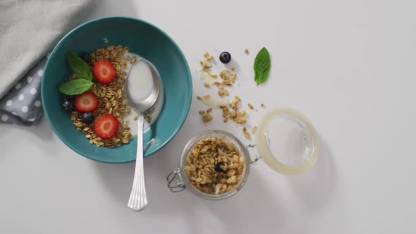 Video of cereals and fruit in ceramic bowl on white kitchen worktop