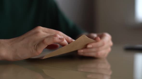 Closeup Hands of Unrecognizable Young Woman Putting Handwritten Christmas Letter Into Envelope and