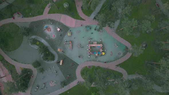 Aerial top view of playground with swings and carousels in city park.