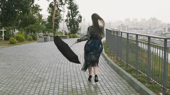 Positive Woman with Umbrella Runs on City Park at Rain