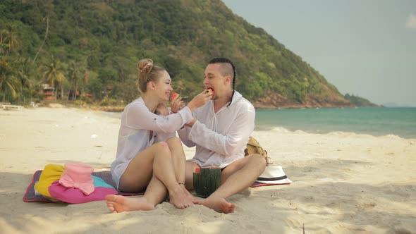 The Cheerful Love Couple Holding and Eating Slices of Watermelon on Tropical Sand Beach Sea