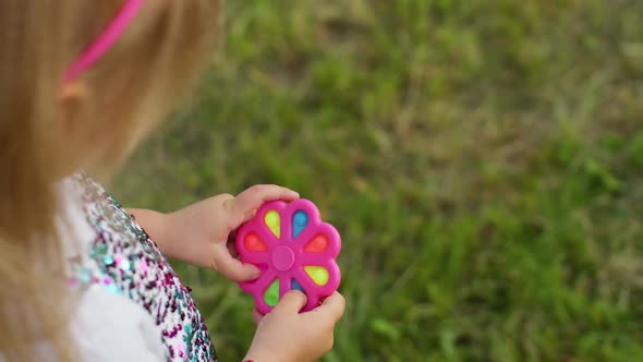 Closeup of Girl Playing Spinning with Pop It Sensory Antistress Toy in Park Stress Anxiety Relief