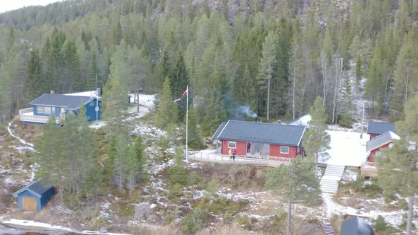 Man and woman flying a drone from a small house on a mountain with thick forest and a natural lake i