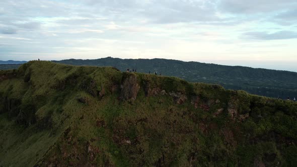 aerial of people trekking on a ridge near crater of Mount Batur volcano at sunrise in Bali Indonesia