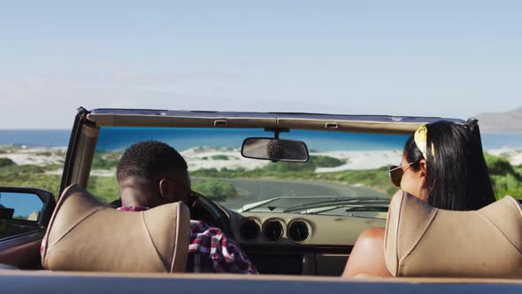 African american couple raising their arms in the air while sitting in the convertible car on road