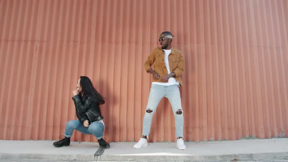 Joyful Young People Mixed Race Couple Dancing Performing Trendy Moves Outdoors Against Wall