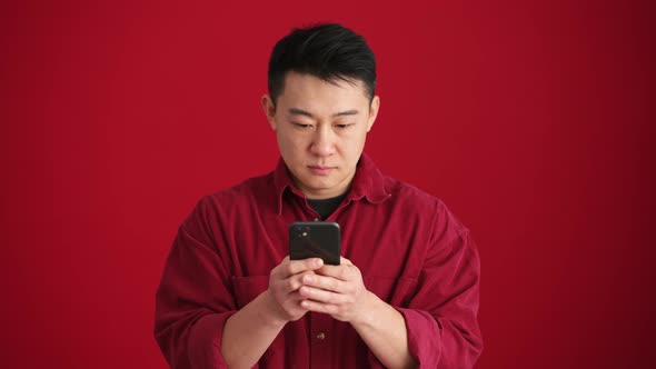 Confident Asian man wearing shirt texting by phone