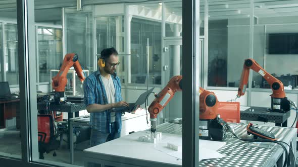 Science Lab with a Moving Robotic Arm Being Observed By a Researcher