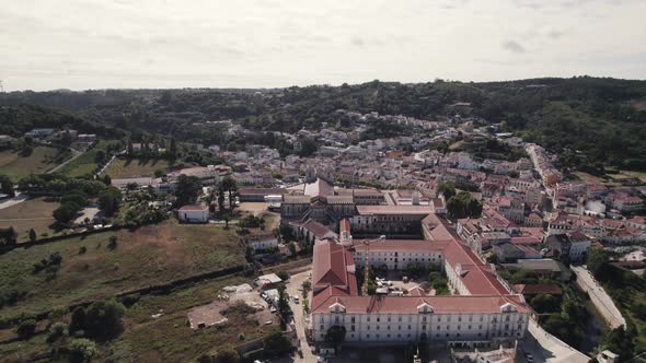 Aerial pull out shot away Alcobaça monastery complex overlooking at cityscape