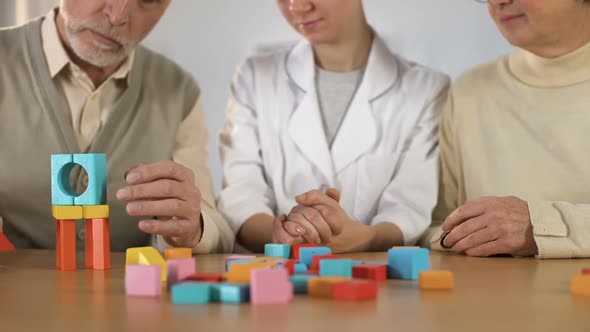 Nurse Supporting Sick Male Making House of Color Wooden Cubes, Rehabilitation