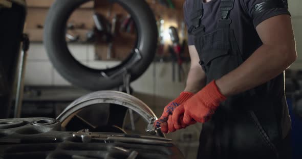 Mechanic Unscrews and Rotates an Alloy Wheel on Tyre Changer Machine on Service