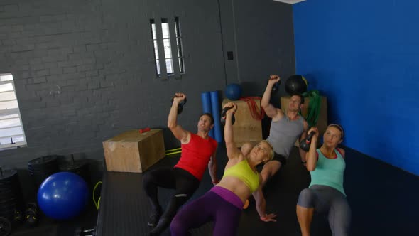 Group of people performing push-up with kettlebell