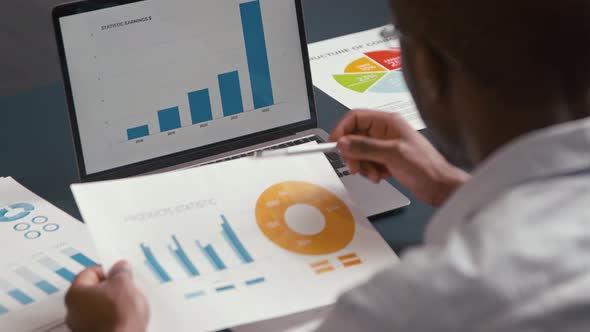 Young businessman working with laptop at the desk in the office. Man viewing corporate company chart