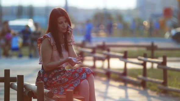 Young Women in a Park is Holding a Smartphone and Typing