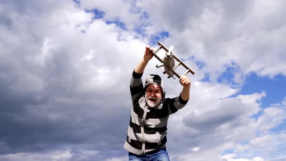 Happy Greybeard Man Pretend Flying on Wooden Airplane in Sky Travelling