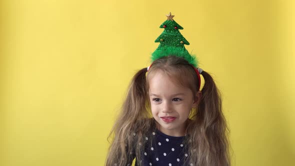 Portrait Emotion Cute Happy Preschool Baby Girl With Ponytail And Christmas Tree on Head Smiling