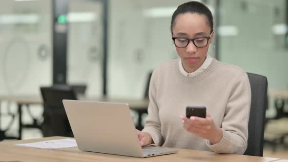 Creative African Woman with Laptop Using Smartphone