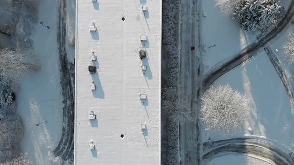 Aerial Top View Person Walking Next to Snow Covered Building Roof Winter Day