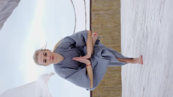 Attractive Blonde Woman in Robe Doing Yoga Eka Pada Utkatasana Outdoors