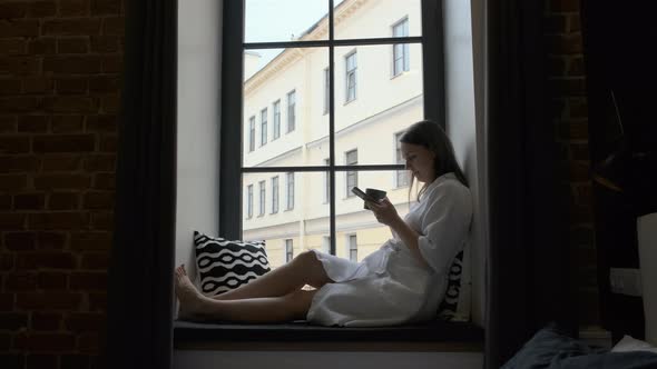 Female Resting on a Windowsill in a Hotel Room