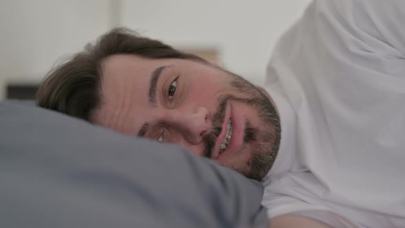 Portrait of Young Man Talking on Video Call While Laying in Bed