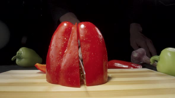 Male Hand Chop Red Sweet Pepper in Half with Sharp Knife