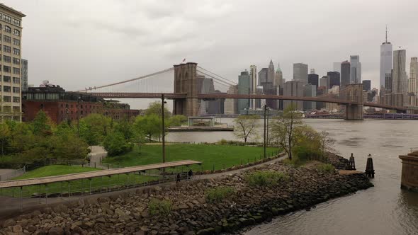 A low angle view over the East River on a cloudy day. The drone dolly in under the Manhattan Bridge,