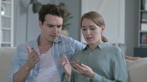 Portrait of Disappointed Couple Getting Upset While Using Smartphone