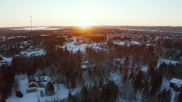 Sunset aerial drone view flying over a snowy residential community with a cell base tower.