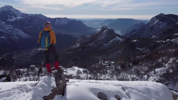 Hiker standing on rock on top of mountains, looking at winter view