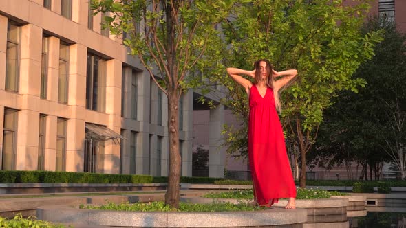 Beautiful Young Girl Dancing on the Street of a Modern Building of a Business Center in the Sunset