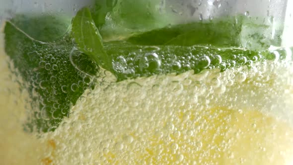 A Refreshing Soft Drink. Mojito Is Poured Into a Glass Close-up. Lemon Mint and Sparkling Water with