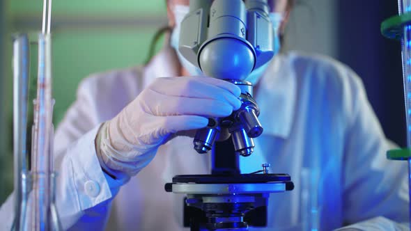 Female Microbiologist Looking Into Microscope in Medical Science Laboratory