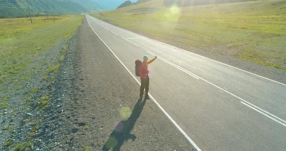 Flight Over Hitchhiker Tourist Walking on Asphalt Road