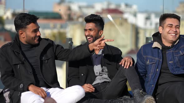 Joyful Young Handsome Middle Eastern Men Talking Laughing Making Jokes Sitting on Rooftop in