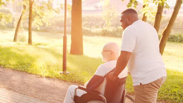 African-American caregiver and old disabled man in a wheelchair. Nurse and patient.