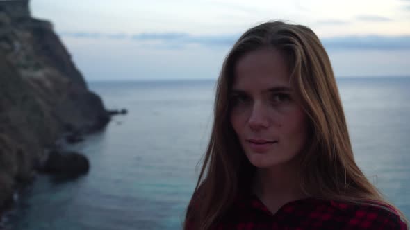 Young Beautiful Sensual Woman Posing High Above the Sea on a Volcanic Rock Like in Iceland