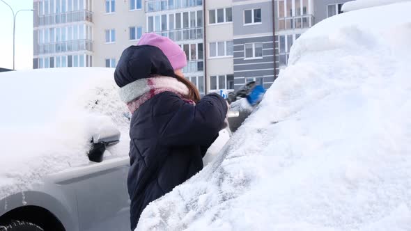 Child a Little Cute Girl Cleans the Car From Snow on a Snowy Winter Day