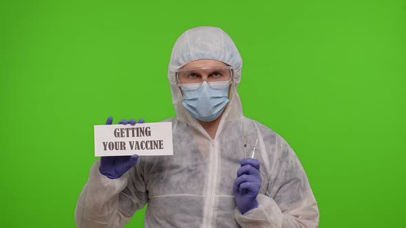 Medical Worker Doctor in PPE Suit with Syringe Ampoule Text Slogan on Paper Getting Your Vaccine